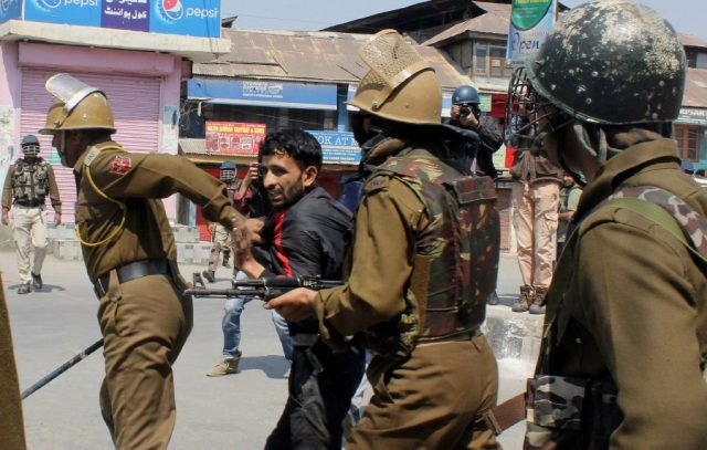 Indian policemen detain a Indian Kashmiri during clashes with Indian police following gun fights between suspected militants and Indian forces in South Kashmir, in Srinagar on April 1, 2018.