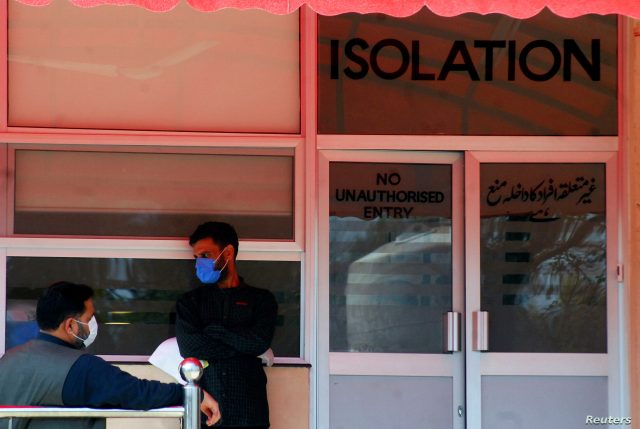 Men wear protective mask as a preventive measure against coronavirus, as they stand outside the Isolation ward at the Pakistan Institute of Medial Sciences in Islamabad
