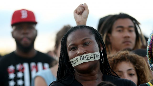 Demonstrators in Miami stand with tape reading, " I Can't Breathe,