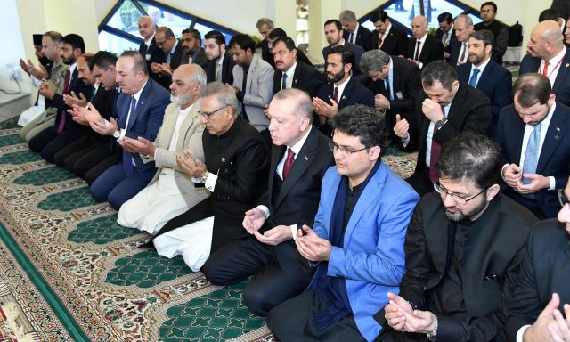Turkish President Tayyip Erdogan along with Pakistan's President Arif Alvi hold palms as they attend Friday prayers at the President House in Islamabad,