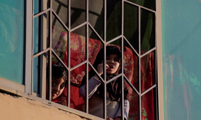 Children look out of their window as they stay home during a government-imposed lockdown in Islamabad