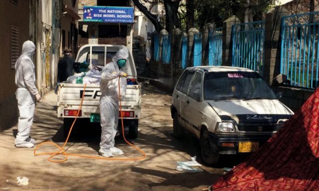 Health workers in Abbottabad spray chlorine water in a street after the death of a coronavirus patient was reported from the area